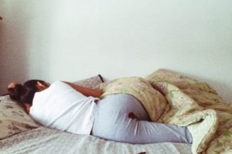 picture of Rupi Kaur in her bed, with period blood on her pants and on her sheet
