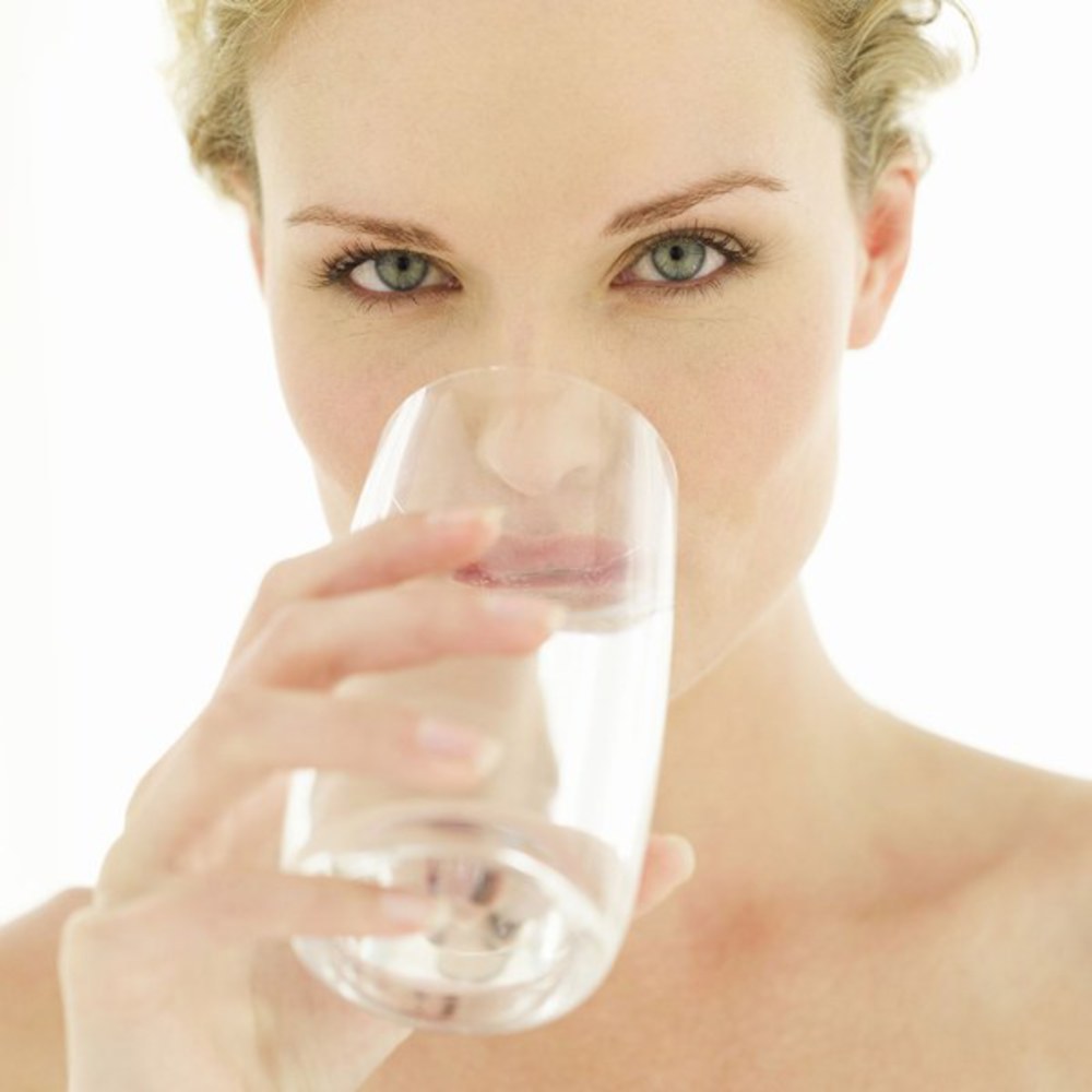 photo d'une femme qui boit un verre d'eau. L'hydratation est le premier secret de la beauté.