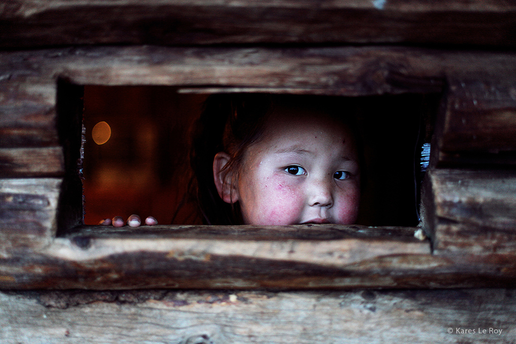 Portrait d'une petite fille qui se cache derrière une porte, extrait du livre 56000 kilomètres de Kares Leroy, Mongolie, Khövsgöl, tribu des Tsaatan