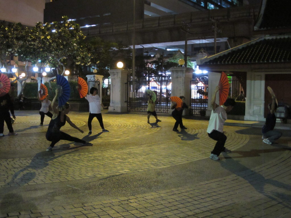Entrainement d'un art martial qui se pratique avec un éventail, dans un parc en plein centre de Bangkok