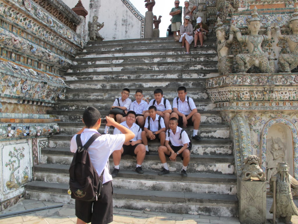 Des étudiants se prennent en photo sur les marches du temple Wat Arun